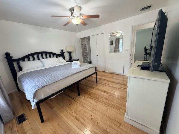 A bedroom with a bed, a ceiling fan, a wardrobe, a mirror, and a television on a cabinet. - Cottonwood Heights Escape/Minutes to Trails & Views (Cottonwood Height)