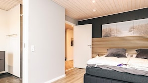 Un dormitorio moderno con cama, armario y techo de madera.