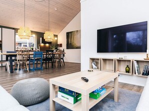 A modern living room with a TV, wooden furniture, and a dining area. - 4 Star Holiday Home in Vaeggerlose (Vaeggerlose)