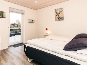 A bedroom with a bed, a nightstand with a lamp, a window, and a painting on the wall. - 4 Star Holiday Home in Vaeggerlose (Vaeggerlose)