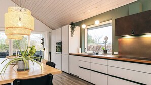 Una cocina moderna con encimera de madera, armarios blancos y una lámpara colgante.