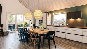 Una cocina moderna con una mesa de comedor de madera, sillas negras y lámparas colgantes.