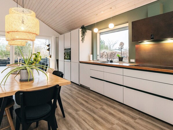 Una cucina moderna con piano di lavoro in legno, mobili bianchi e lampadario.