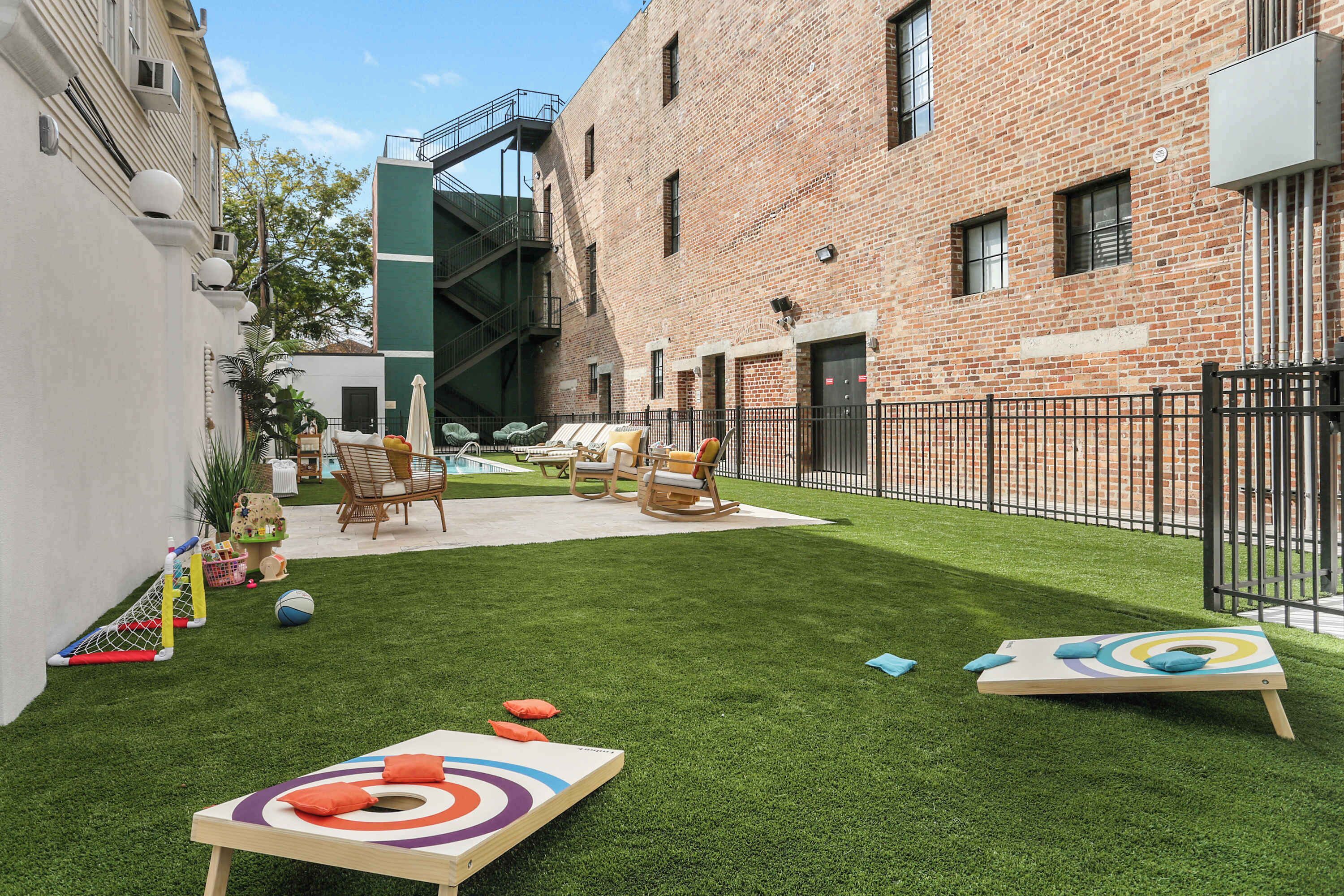 Une cour avec une pelouse artificielle, du mobilier d’extérieur et un espace de jeux pour enfants.