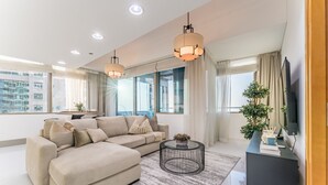 Een moderne woonkamer met een modulaire bank, een ronde salontafel en een televisie op een zwart dressoir.