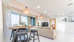 Een moderne woonkamer met een bank, een televisie en een eethoek met krukken.