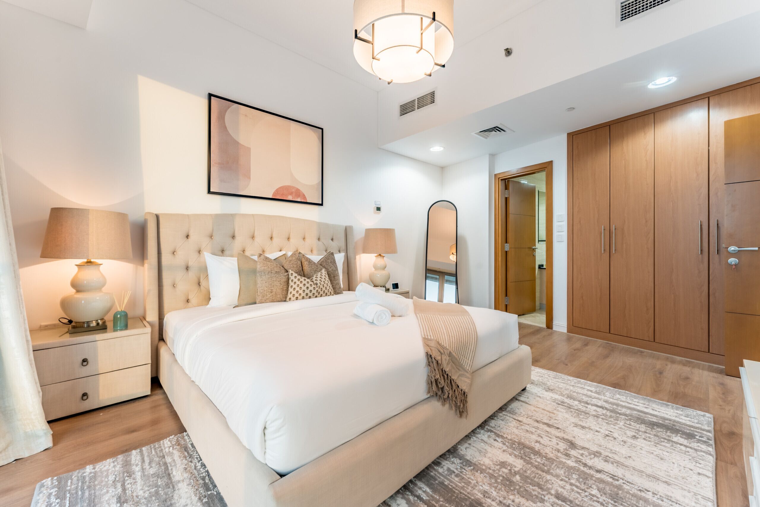 Une chambre moderne avec un grand lit, des lampes de chevet, un miroir et une armoire.