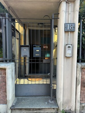 A gated entrance with a mailbox and a utility box, number 18 on the pillar. - Constance and Marco's small manor house (Milano)