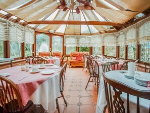 A dining area with round tables, chairs, and a central seating area with a sofa. - Standard Single Room (Gateshead)