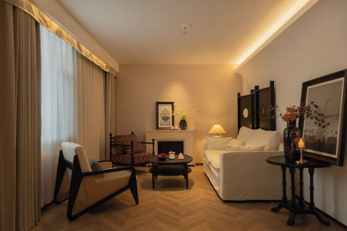 Ein helles Wohnzimmer mit Kamin, einer Couch, einem Sessel und einem kleinen Tisch.