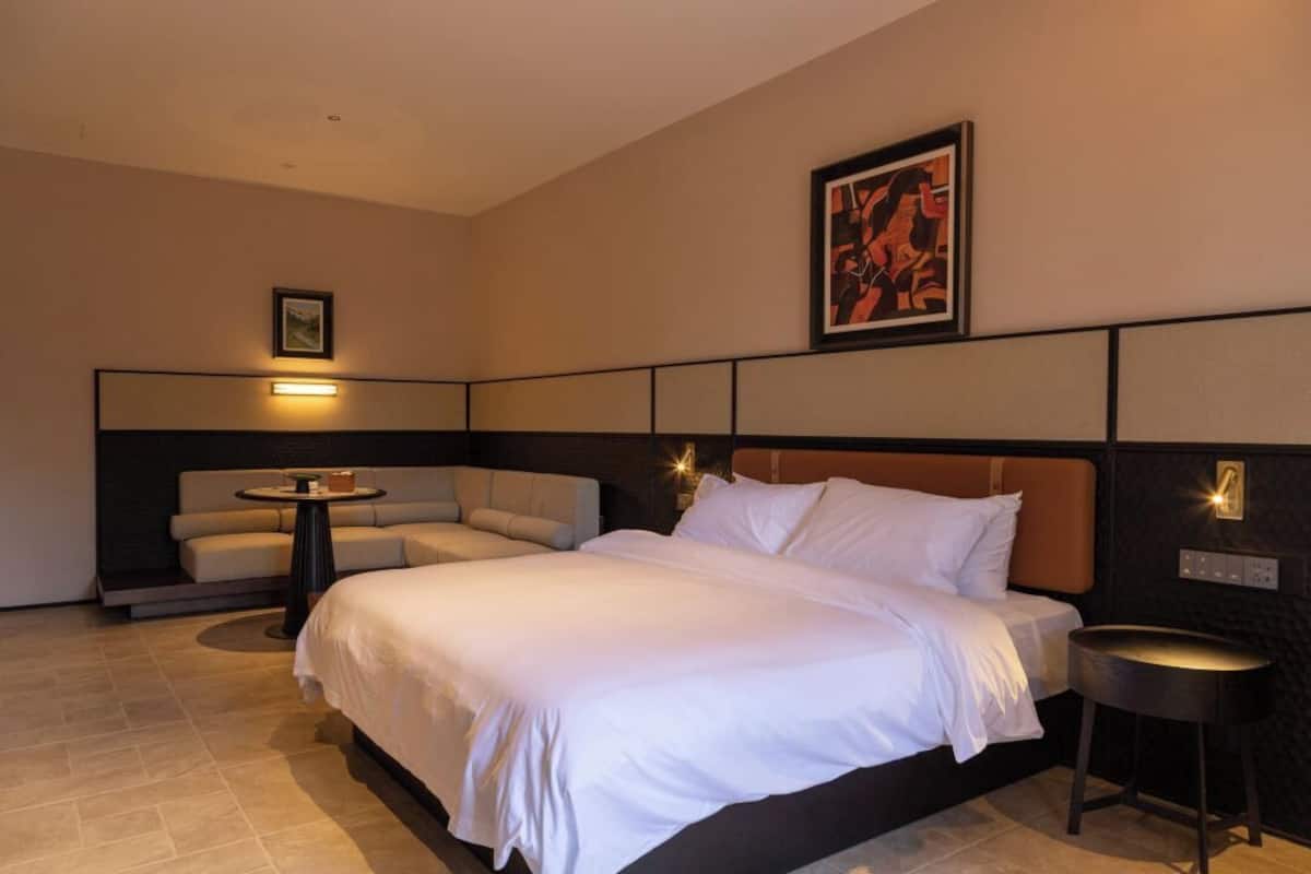 Ein Hotelzimmer mit einem großen Bett, einer Couch, einem kleinen runden Tisch und einem Bild an der Wand.