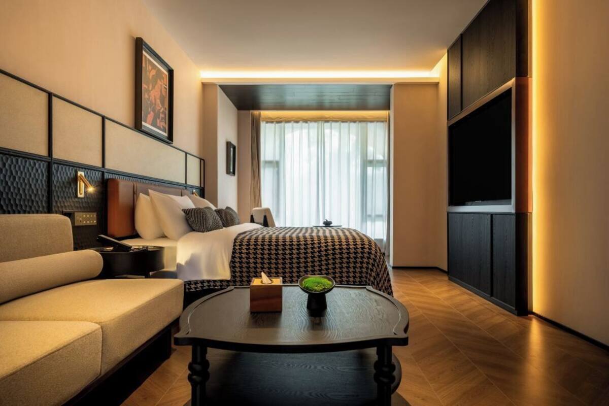 Ein modernes Hotelzimmer mit Bett, Sofa und Couchtisch.