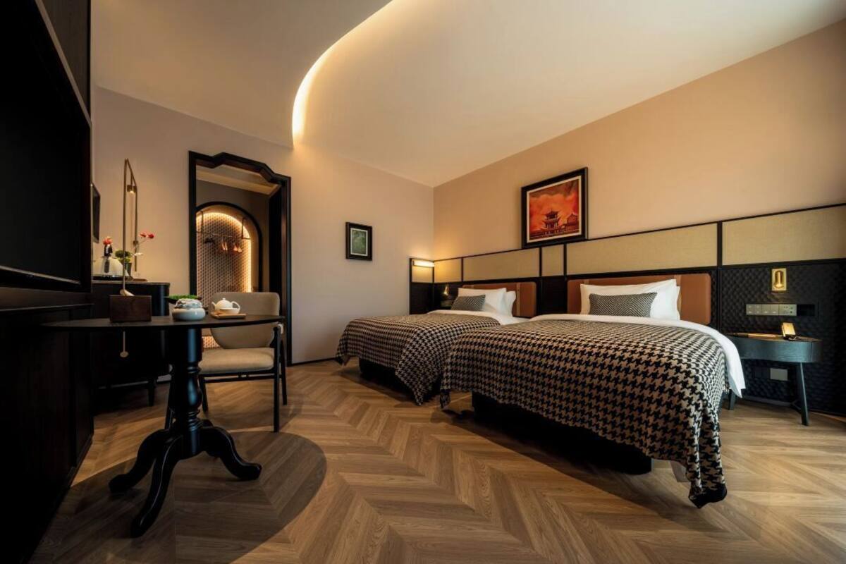 Ein Hotelzimmer mit zwei Betten, einem Schreibtisch und einer gewölbten Decke.