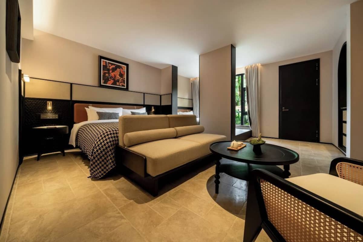 Ein modernes Hotelzimmer mit Bett, Sofa und einem kleinen Esstisch.