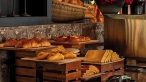 Mostrador de panadería con diferentes productos horneados y un florero decorativo con flores rojas.