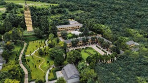 Un bâtiment traditionnel surmonté d’une tour de style pagode, entouré de jardins et de sentiers bien entretenus.