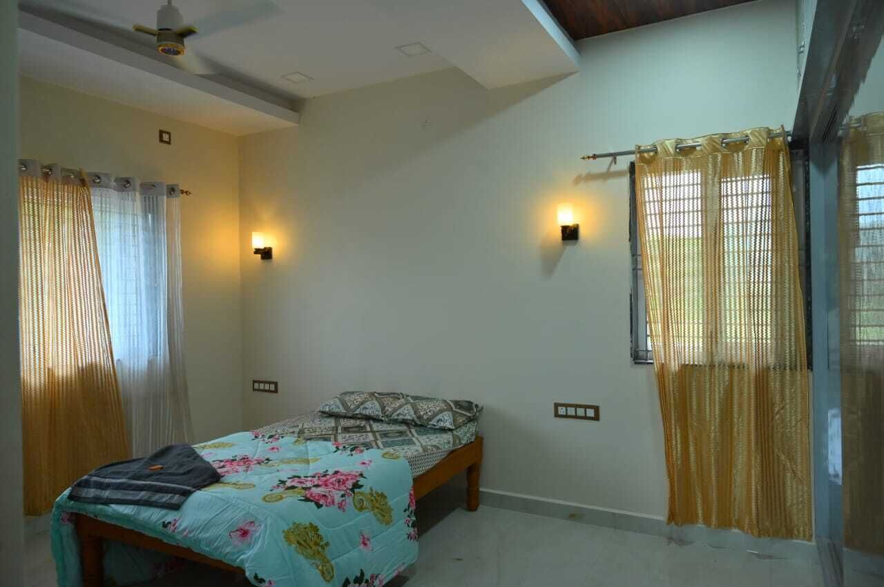 Un dormitorio con cama, cortinas e iluminación en la pared.