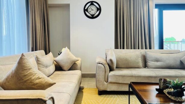 Un salon moderne avec deux canapés, une table basse et une horloge murale.