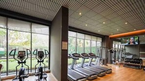 Une salle de sport moderne équipée de tapis de course, de vélos elliptiques et de matériel de musculation.