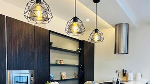 Une cuisine moderne dotée d’un îlot central, de tabourets de bar, de luminaires suspendus et d’une hotte de cuisine en acier inoxydable.
