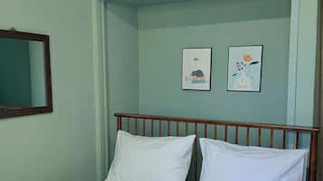 A bed with white bedding, a wooden headboard, and two framed pictures on the wall.