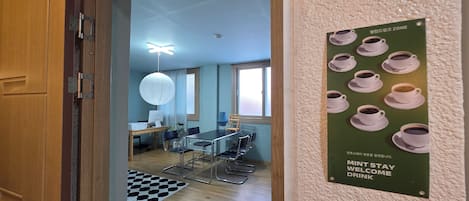 A room with a desk, chairs, a hanging light fixture, and a poster on the wall.