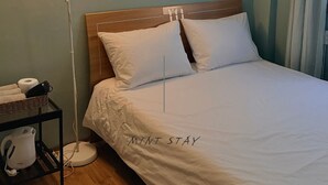 Une chambre d’hôtel avec un lit, une table de chevet avec une lampe, un tableau au mur et un rideau.