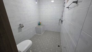Une petite salle de bain moderne, équipée de toilettes, d’une douche et d’un meuble de rangement.