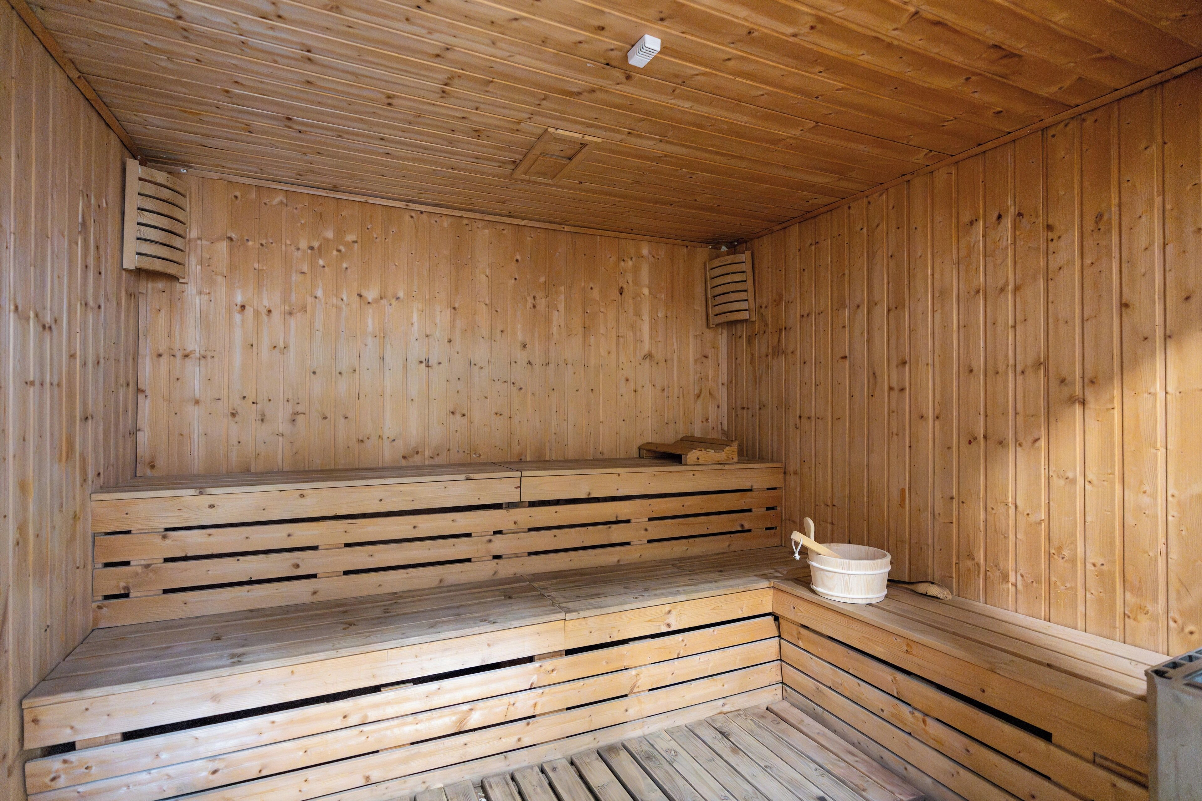 Una sauna in legno con panche e un catino.