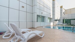 Un espace piscine intérieur moderne, avec des murs recouverts de carreaux blancs et une eau cristalline.