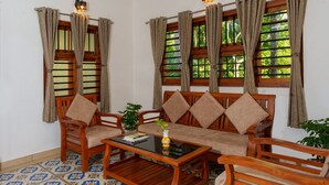 A cozy room with a sofa set, two armchairs, a coffee table, and a patterned floor.