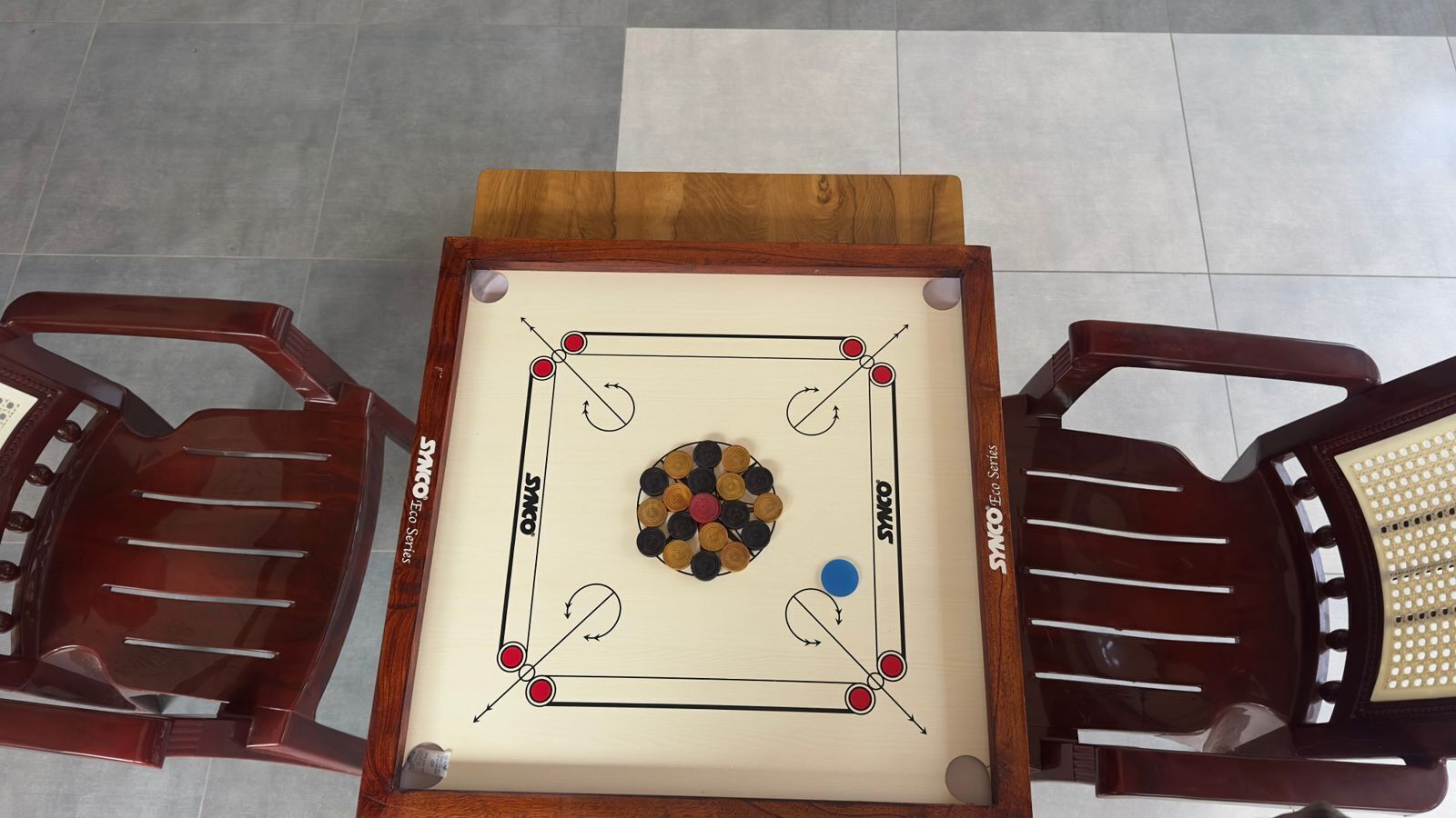 Een biljart met houten frame, twee stoelen en een wit poolbal.
