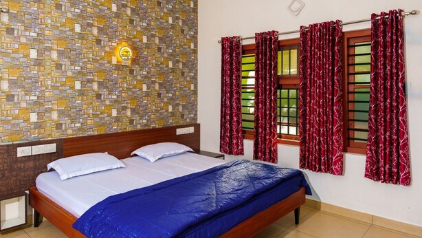 A room with a bed, a stone mosaic wall, and red curtains.