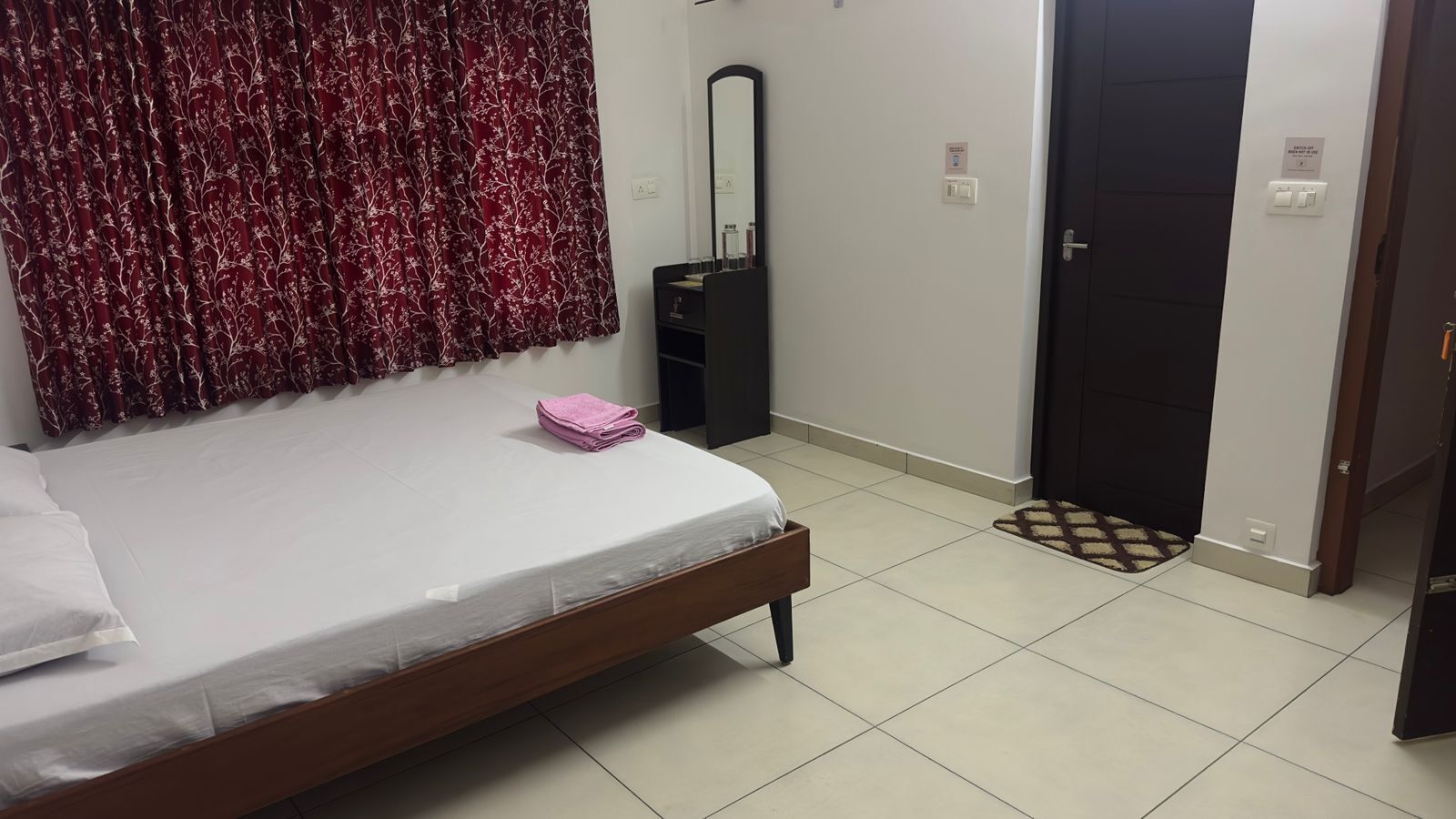 A bedroom with a bed, a mirror, a wardrobe, and a door.
