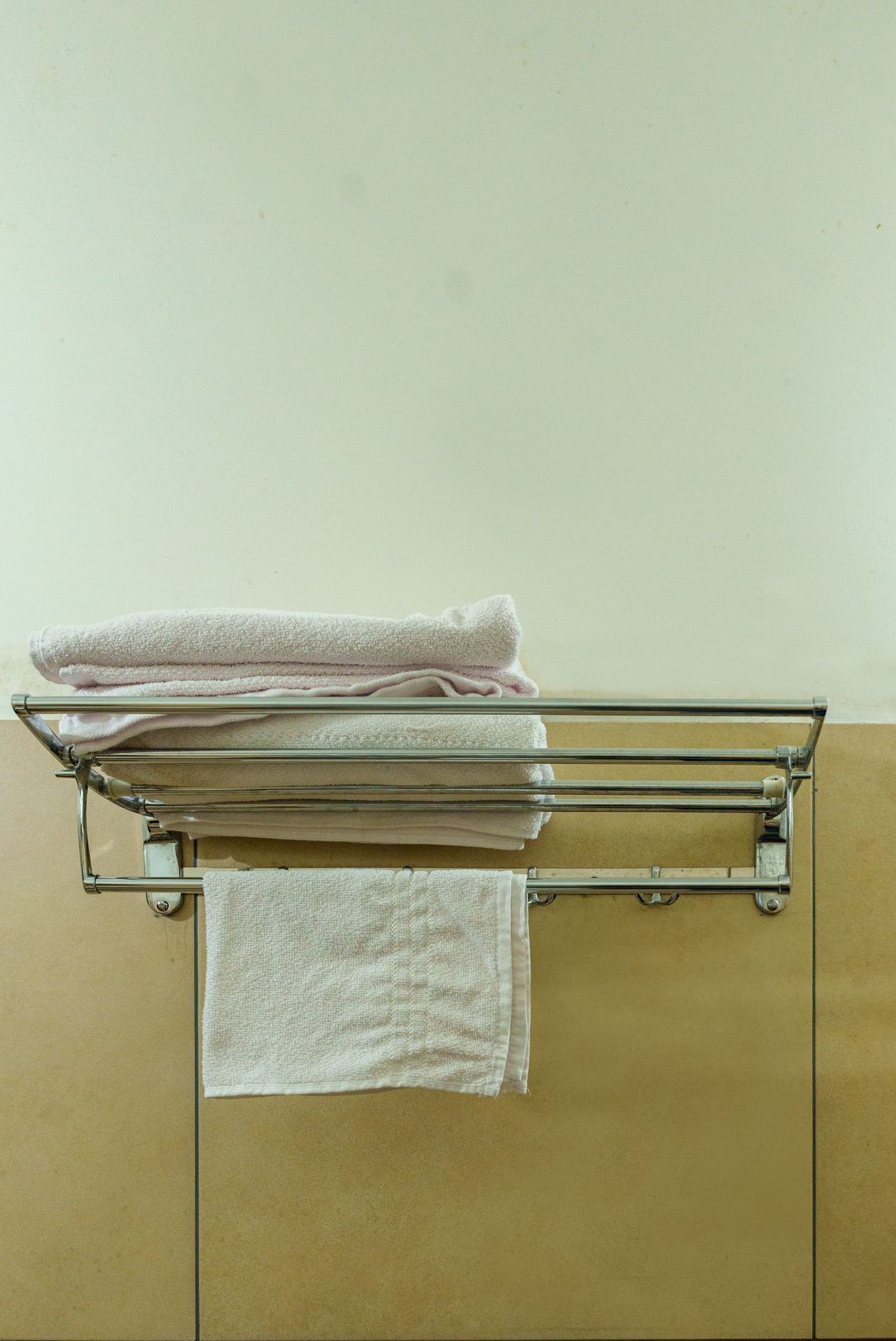 A bathroom with a glass towel rack holding folded towels.