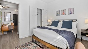 Ein Schlafzimmer mit Bett, Nachttischen, einem Schminktisch, einem Schrank und einem Deckenventilator.