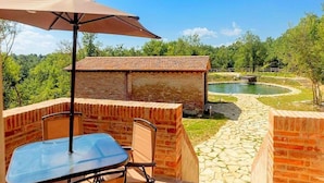 Un patio exterior con mesa y sillas, un muro de ladrillo y vistas a un estanque.