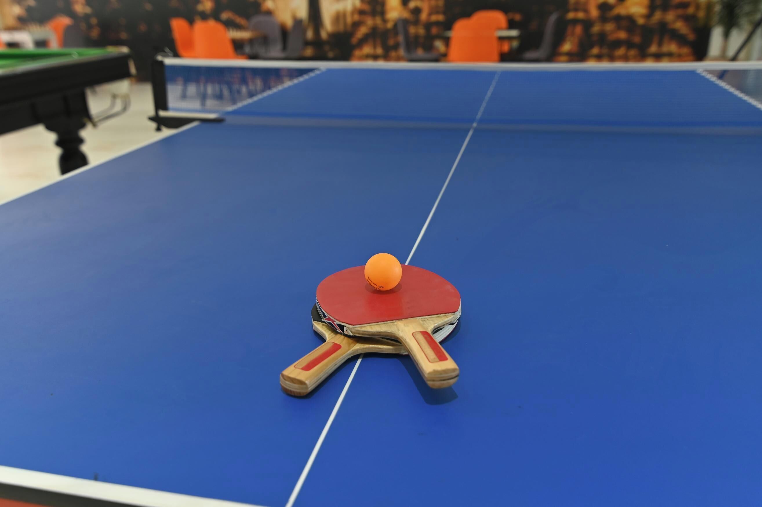 A table tennis table with a ball and paddle.