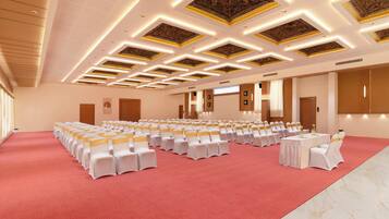 A large conference room with rows of white chairs, a central table, and a red carpet.