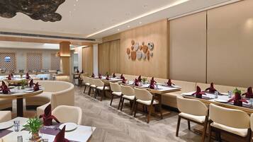 A spacious dining area with multiple tables, chairs, and a decorative wall with abstract art.