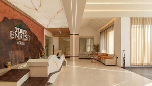 Eine moderne Hotelhalle mit Rezeption, Sitzgelegenheiten und einer großen Marmorwand.