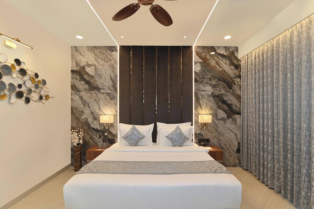 Habitación de hotel moderna con una cama grande, pared de mármol, ventilador de techo y decoración mural.