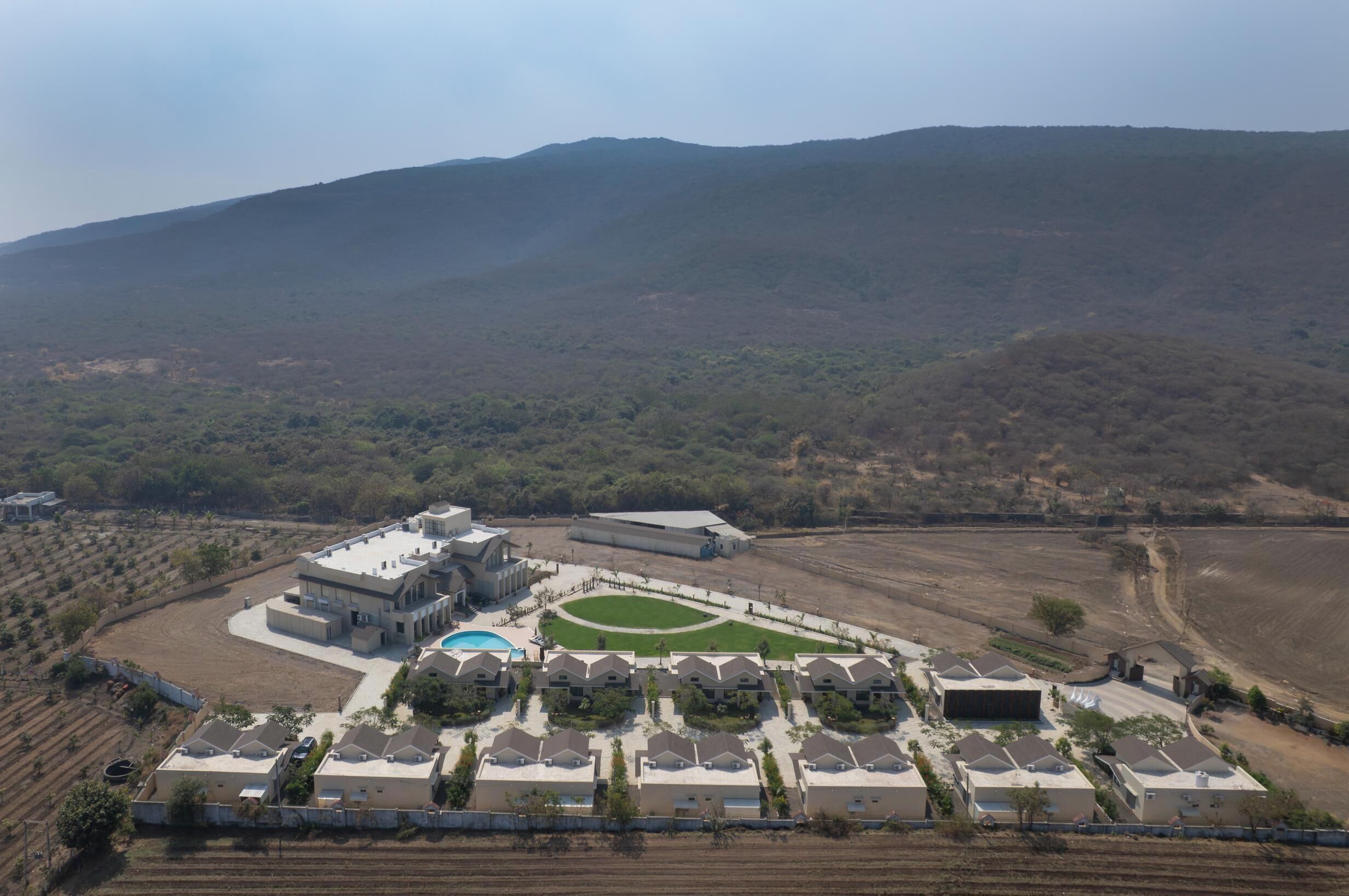An aerial view of a residential area with houses, a swimming pool, and a large building with a flat roof.