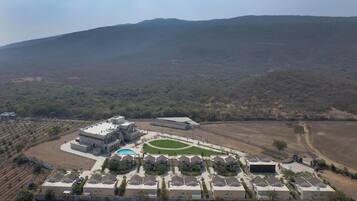 An aerial view of a residential area with houses, a swimming pool, and a large building with a flat roof.
