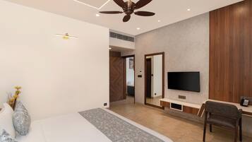 A modern bedroom with a bed, a ceiling fan, a TV, and a desk with a chair.