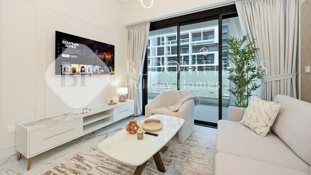 Ett modernt vardagsrum med en stor TV, en soffa, ett soffbord och en balkong med gardiner.