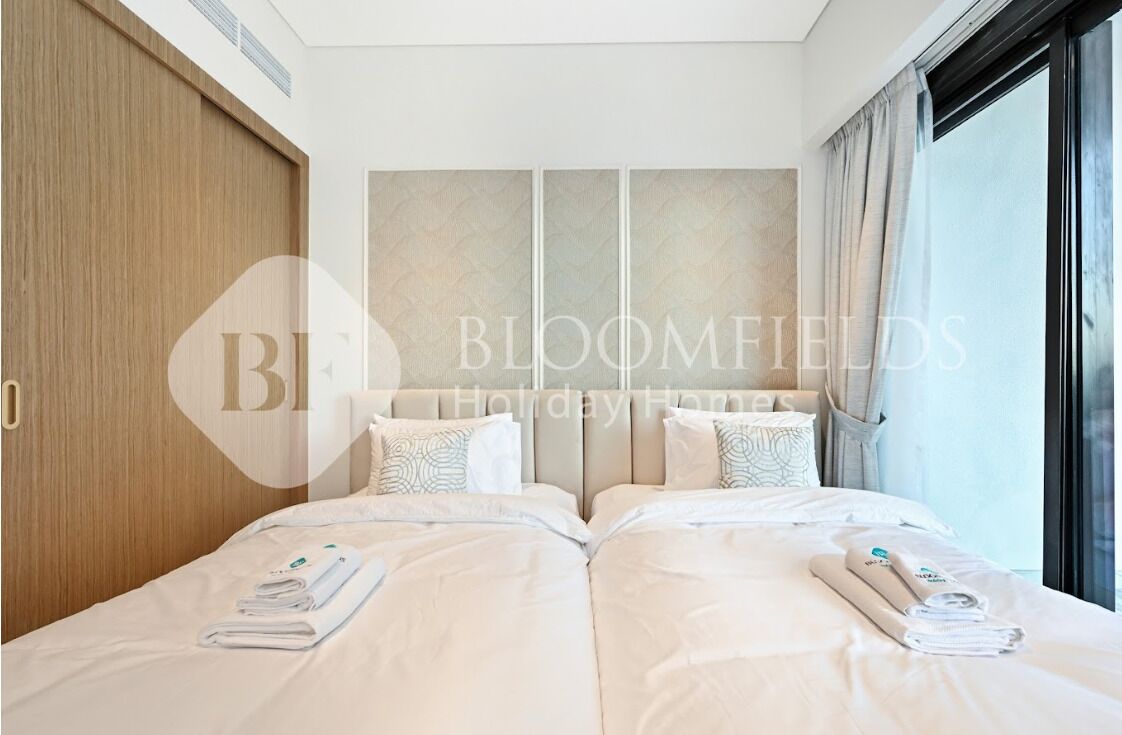 A hotel room with two beds, a large window, and a wooden wardrobe.