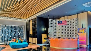 Una hall moderna con un divano blu, una reception e una parete decorativa con la bandiera malese.