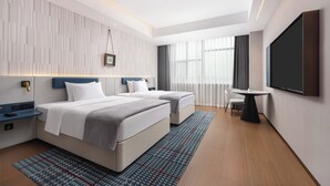A modern hotel room with two beds, a desk, a TV, and a view of the city through large windows. - Wanda Moments Neo Qiemo (Qiemo)