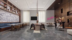 A modern interior with a dining area, a seating area, and a wall with a map design. - Wanda Moments Neo Qiemo (Qiemo)